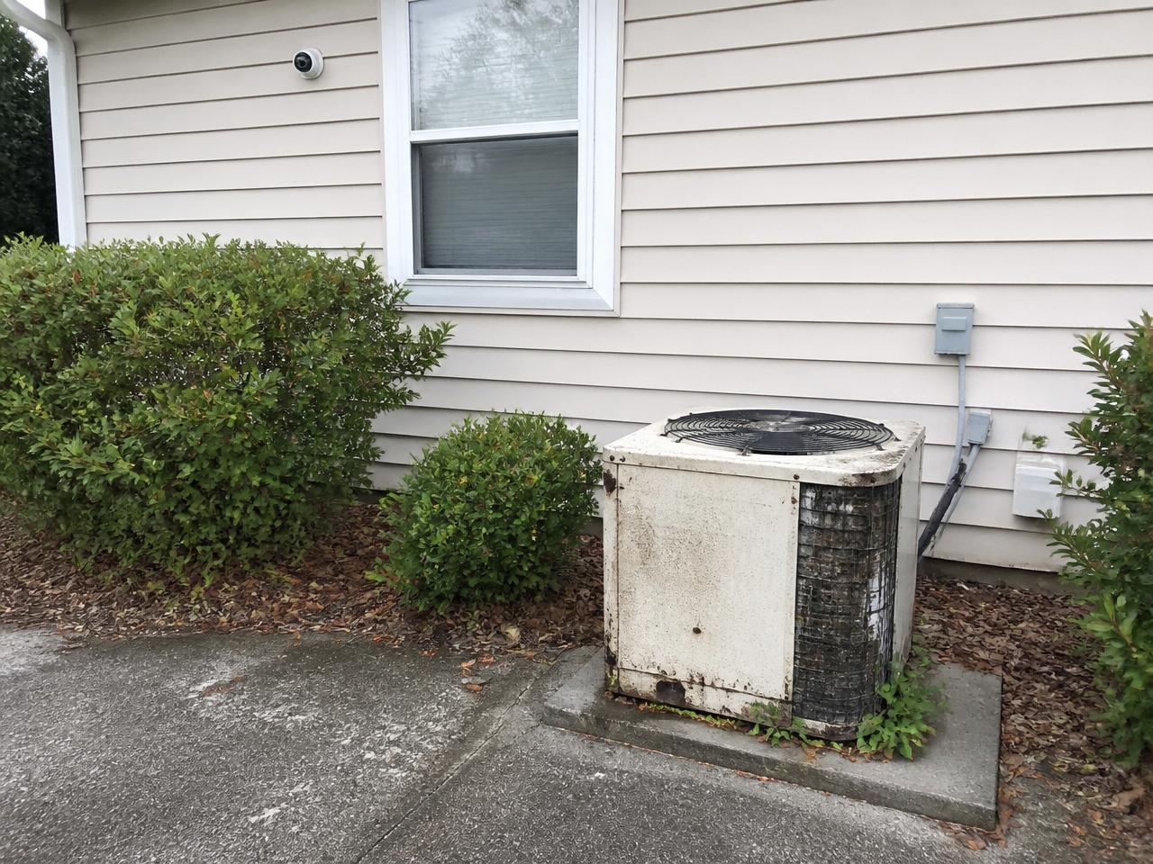 Before: Same-location before: rusted aging condenser on the side of a beige-siding home